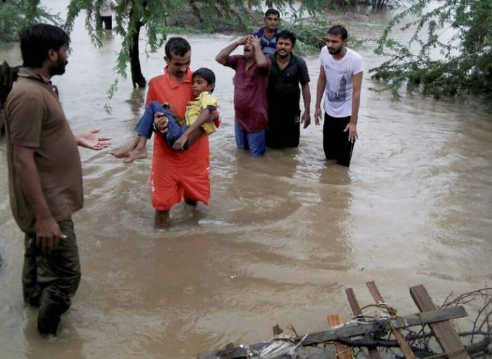 People wade through floodwaters after heavy rainfall in