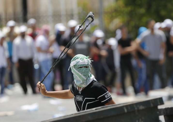 A Palestinian uses a slingshot against Israeli soldiers