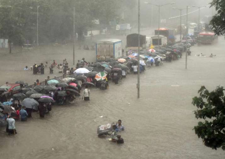 People walk along a flooded street during heavy rain