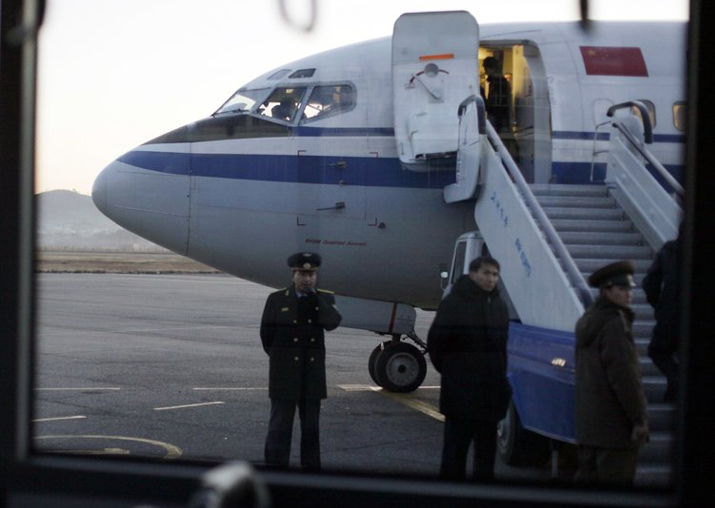File - North Korean officials wait for passengers to board
