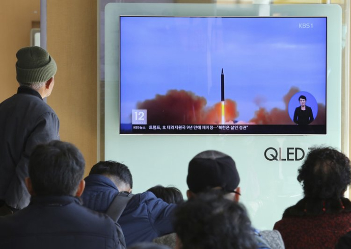 People watch a TV screen showing file footage of North