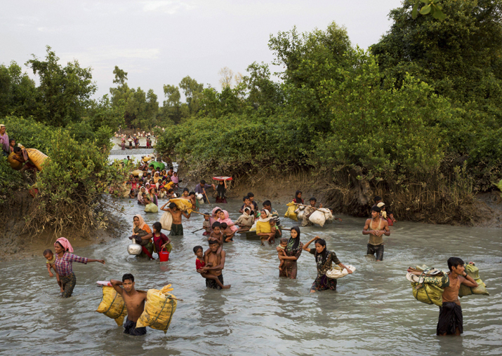 Rohingya wade through the Naf river after having just