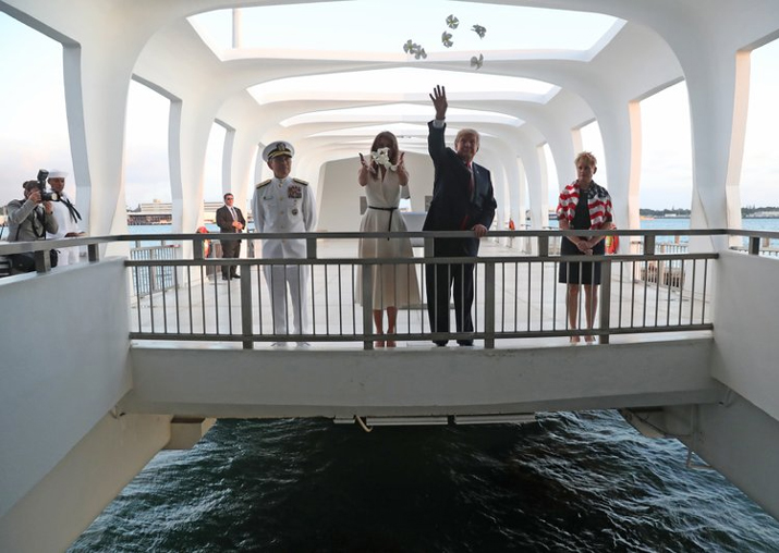Donald Trump and Melania Trump offer flowers at the USS