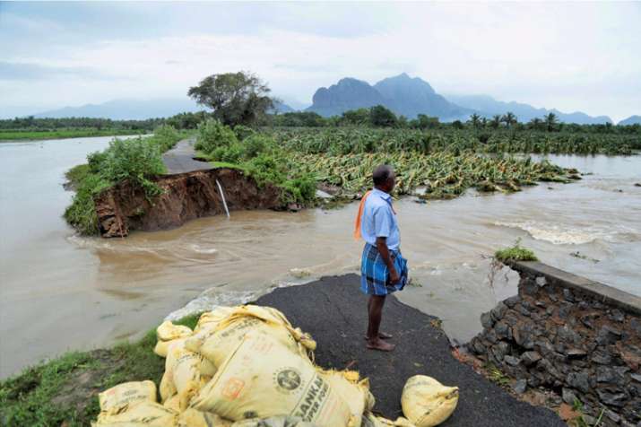 A man watches a road that has been cut off due to floods