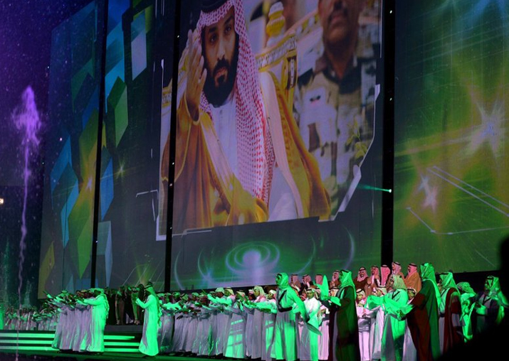 FILE - Saudi men perform under a giant screen showing an