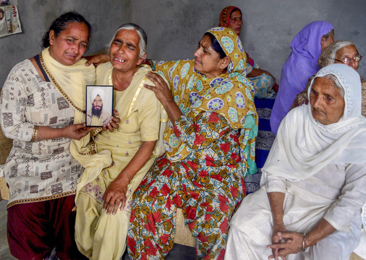Family members grieve by a portrait of one of the 39 Indian