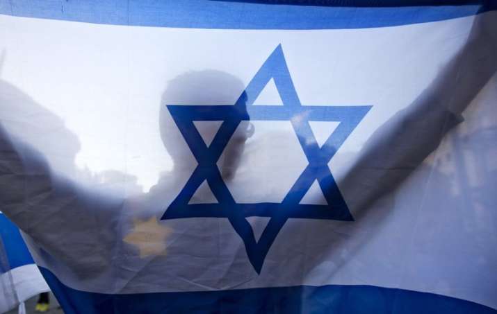 A right-wing Israeli holds a flag and wears a Star of David