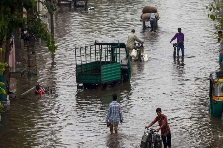 India Tv - People move through a flooded street after heavy rains, in Ahmedabad on Sunday, June 24.  