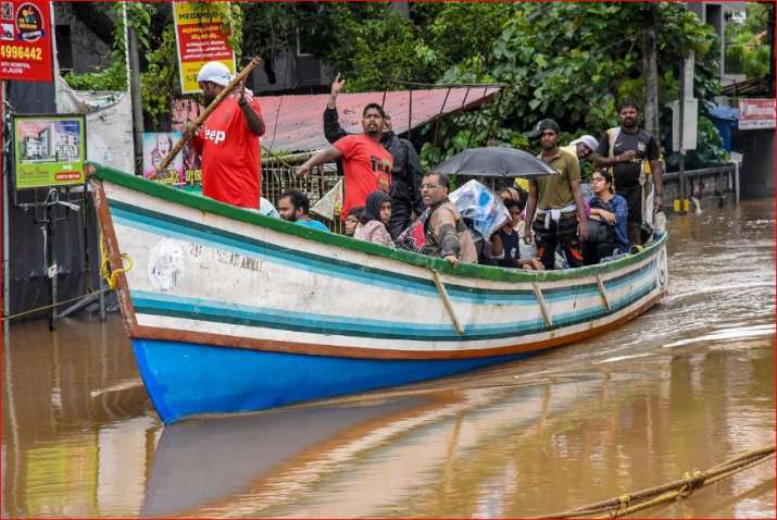 India Tv - Rescue workers row a boat carrying locals who were stranded in floods following heavy monsoon rainfall, in Kochi 