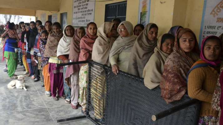 Voters standing in a queue at a polling booth to cast their