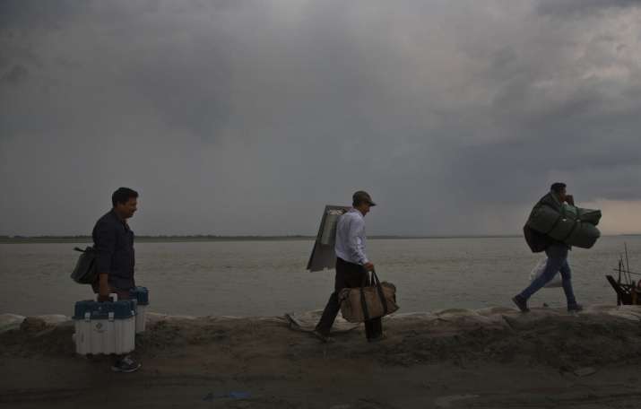India Tv - Election officials carry election material after disembarking from a ferry through the river Brahmaputra ahead of first phase of elections at Nimati Ghat in Jorhat, Assam, India, Tuesday, April 9, 2019. India's general elections will be held in seven phases starting April 11.