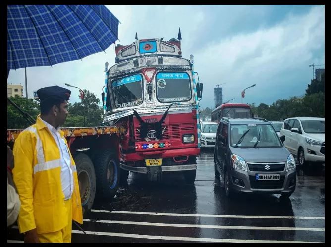 India Tv - Traffic jams and rain-related accidents have become prevalent in the city. In this picture of Navi Mumbai, a traffic police constable manages traffic after a truck collided with a trailor on Uran Phata Flyover causing heavy traffic jam during rainfall on Sunday.