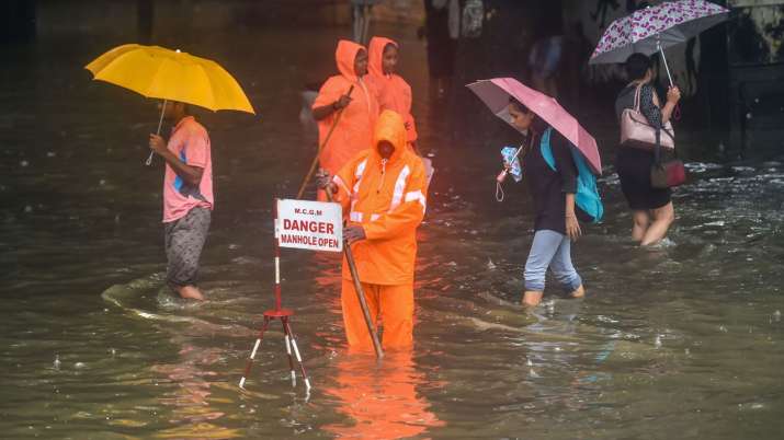 India Tv - A Municipal officer stands guard to warn pedestrians of an open manhole on a waterlogged street following rainfall in Mumbai, India, Friday, June 28, 2019.