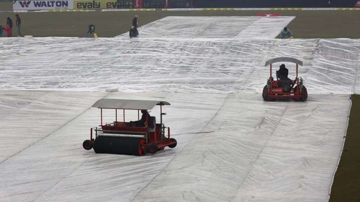 Ground staff work to dry the pitch and field following a