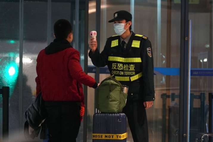 An airport staff member uses a temperature gun to check