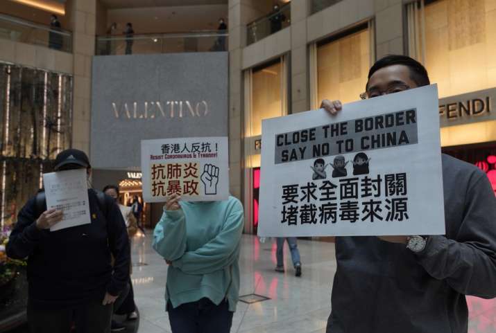 Protesters hold placards reads "Close the border, say no to China" during a protest at a mall in Hon