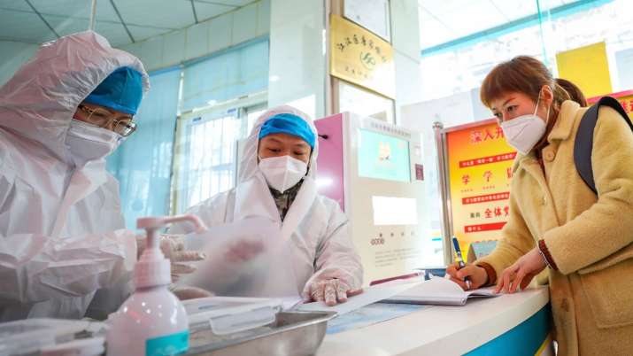 Medical workers in protective gear talk with a woman who