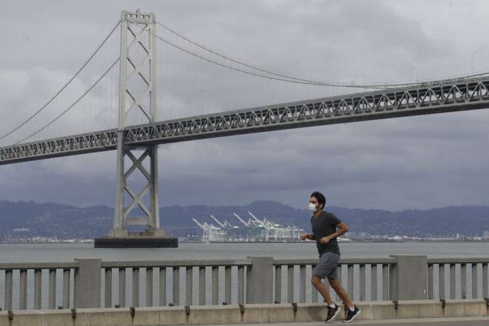 A man wears a mask to protect himself from the coronavirus while running in front of the San Franci