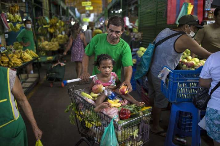 In this March 18, 2020 photo, Cesar Alegre, accompanied by his 4-year-old daughter Lia, places a dam