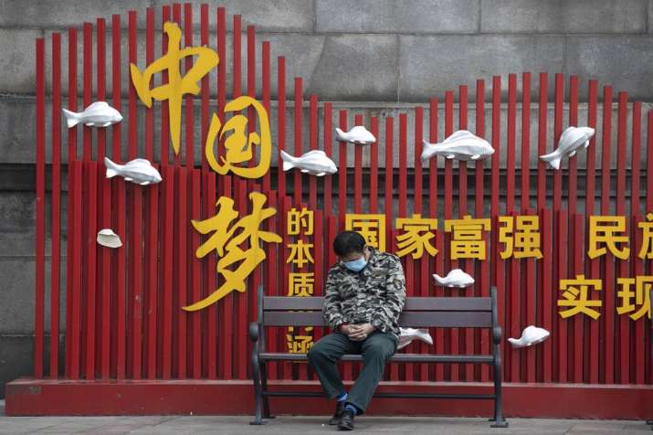 In this April 1, 2020, photo, a resident wearing a mask against the new coronavirus naps on a bench