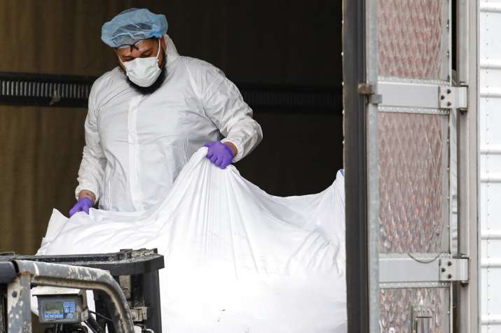 A body wrapped in plastic is loaded onto a refrigerated container truck used as a temporary morgue b