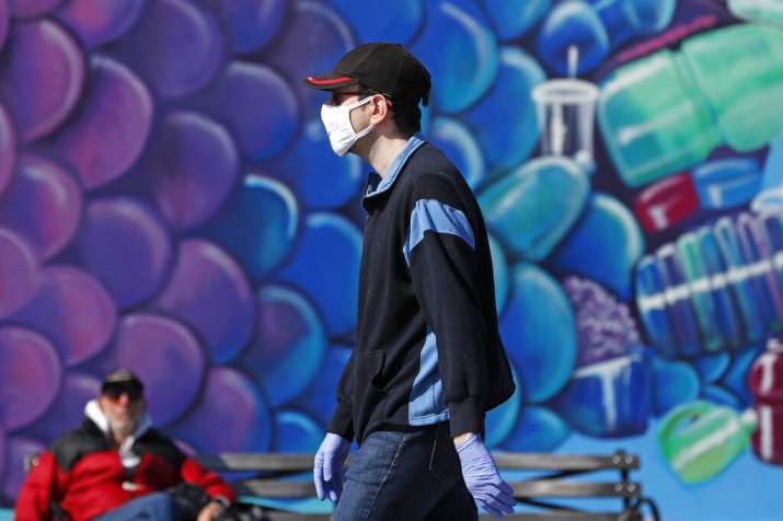 A pedestrian wears a face mask as he walks past a mural of a fish while strolling on the boardwalk a