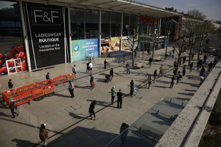 People observe social distancing in an attempt to stop the spread of coronavirus by standing behind
