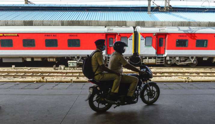 Policemen patrol on a bike along a stationed train during