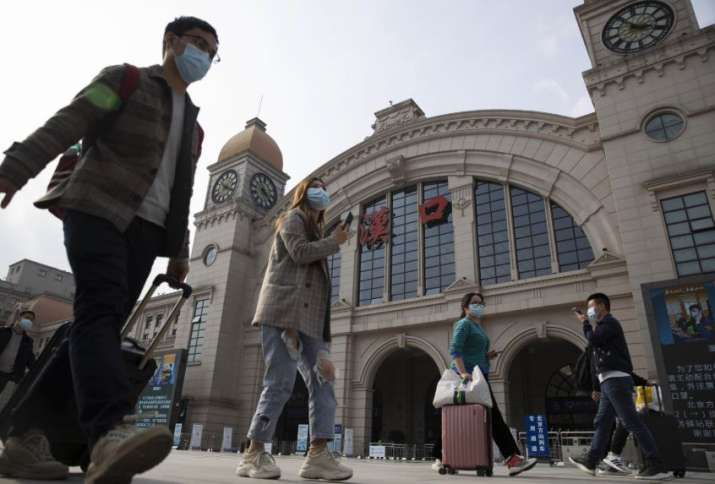 India Tv - Wuhan: Travelers with their luggage walk past the Hankou railway station on the eve of its resuming 