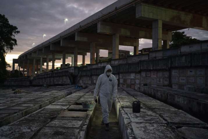 Cemetery worker Bruno Avelino walks among graves as he waits for the arrival of a coffin that contai