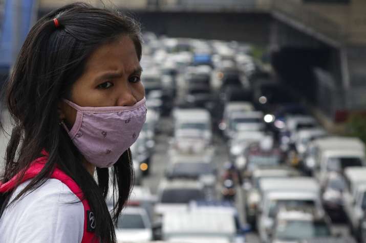 A woman wearing a protective mask looks as traffic builds up during the first day of a more relaxed