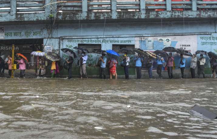 India Tv - Mumbai: Pedestrians cross a waterlogged street during heavy rains, at at Byculla area in Mumbai, Wednesday, Aug. 5, 2020. 