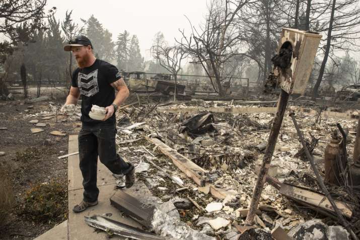 Derek Trenton from Talent, Ore. salvages some items at his parents home as wildfires devastate the 