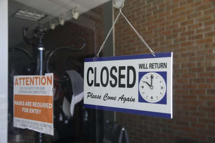 In this July 18, 2020 file photo a closed sign hangs in the window of a barber shop in Burbank, Cali