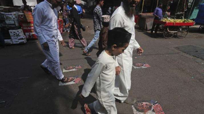 Protesters walk on defaced images of French President Emmanuel Macron pasted on a street in Mumbai,