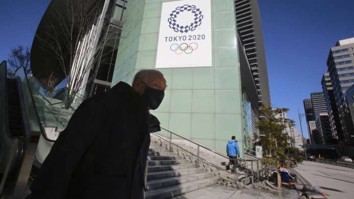 A man walks by the logo of Tokyo Olympic Games planned to