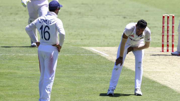 India's Navdeep Saini, right, reacts after injuring his leg