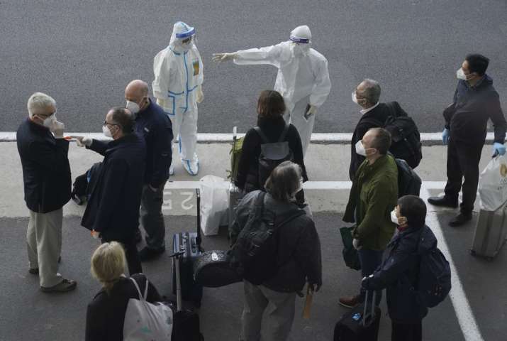 A worker in protective coverings directs members of the World Health Organization (WHO) team on thei