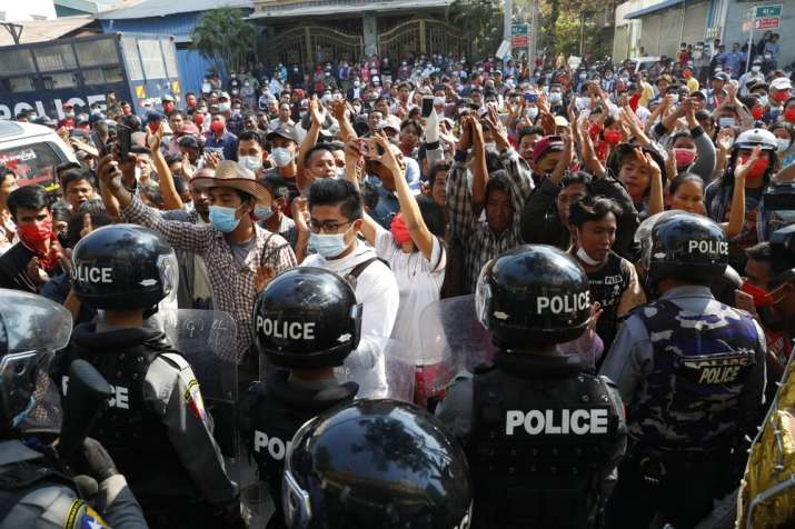 Residents and protesters face riot police as they question them about recent arrests made in Mandala