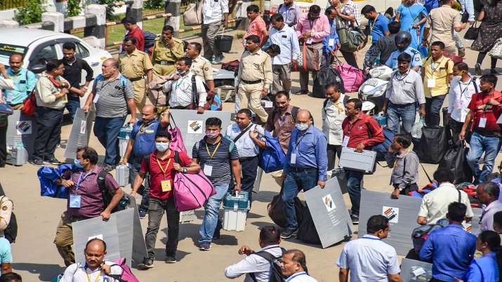 Polling officials carry Electronic Voting Machines (EVMs)