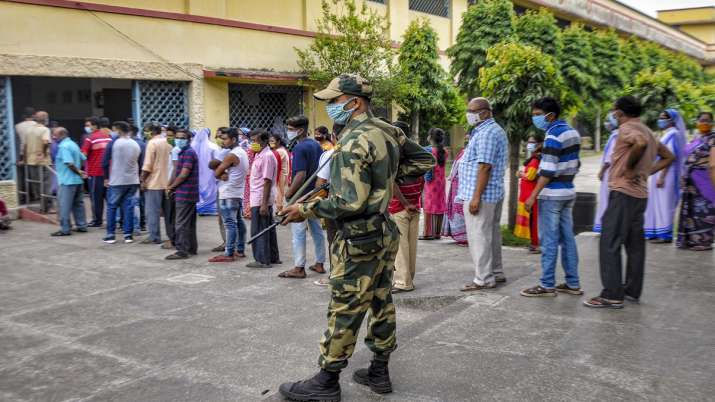 People stand in a queue to cast their votes at a polling