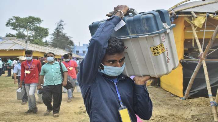 Polling officials carrying Electronic Voting Machines