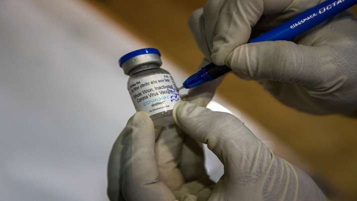 A health worker writes the date and time on a vial of the