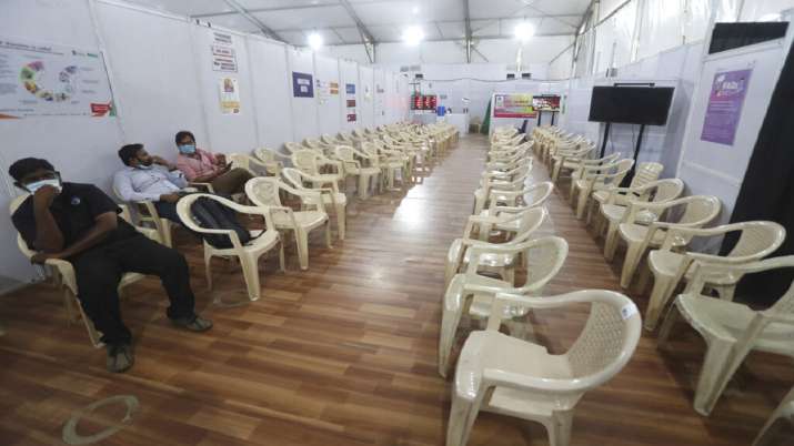 Health workers sit in the waiting area of vaccination