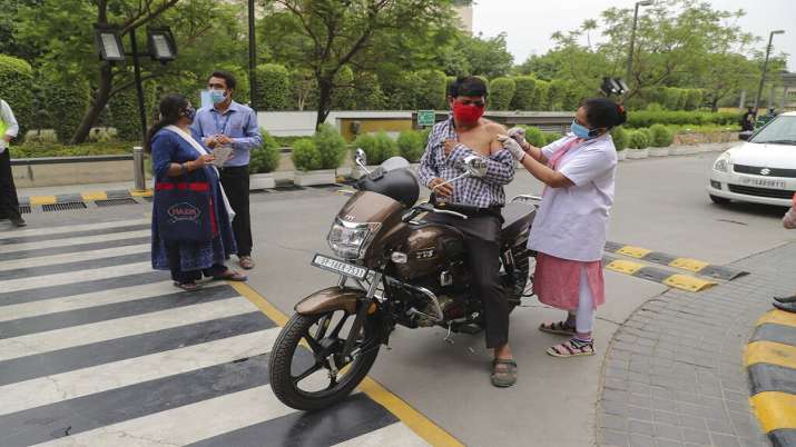 A man on a motorcycle gets inoculated against COVID-19