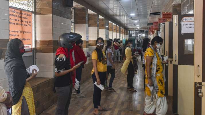 Beneficiaries wait in a queue to receive the COVID-19