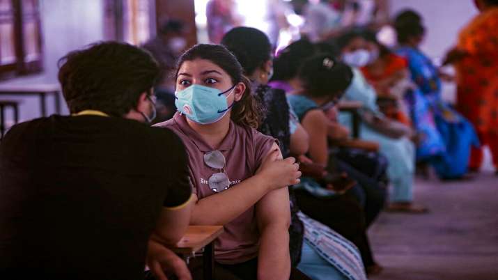 People sit holding their arms after receiving COVID-19
