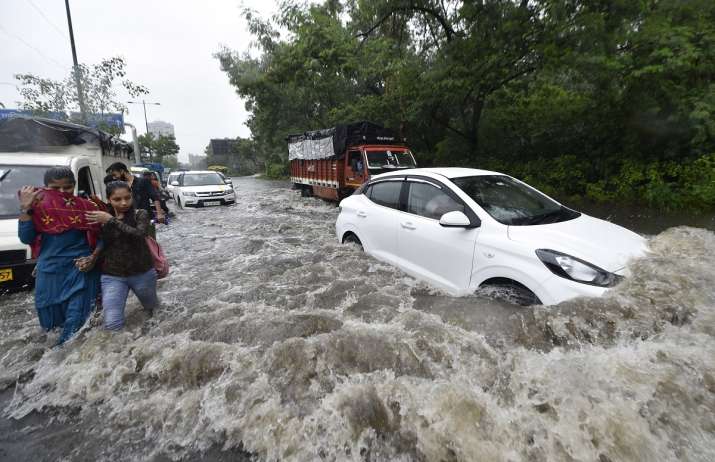 Commuters wade through a waterlogged street due to heavy