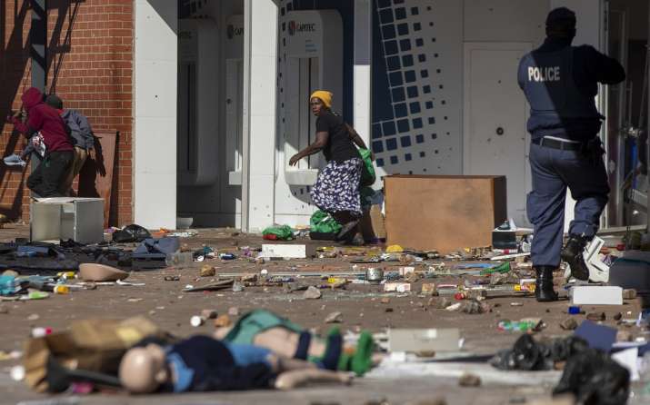 India Tv - People run for cover as a police officer fires rubber bullets while attempting a robbery at the Letshoe shopping center in Katalhong, east of Johannesburg, South Africa.