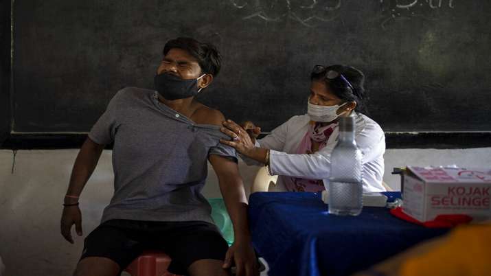 A man reacts as a health worker inoculates him against the